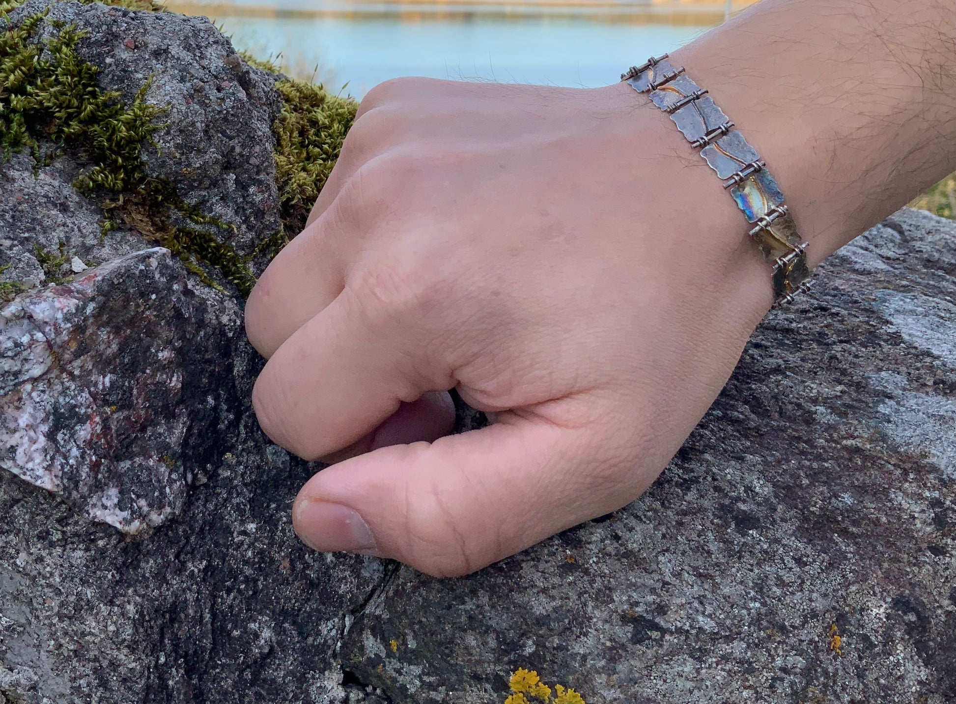 Handmade viking style bracelet Rogue Sea   On wrist against rocky surface