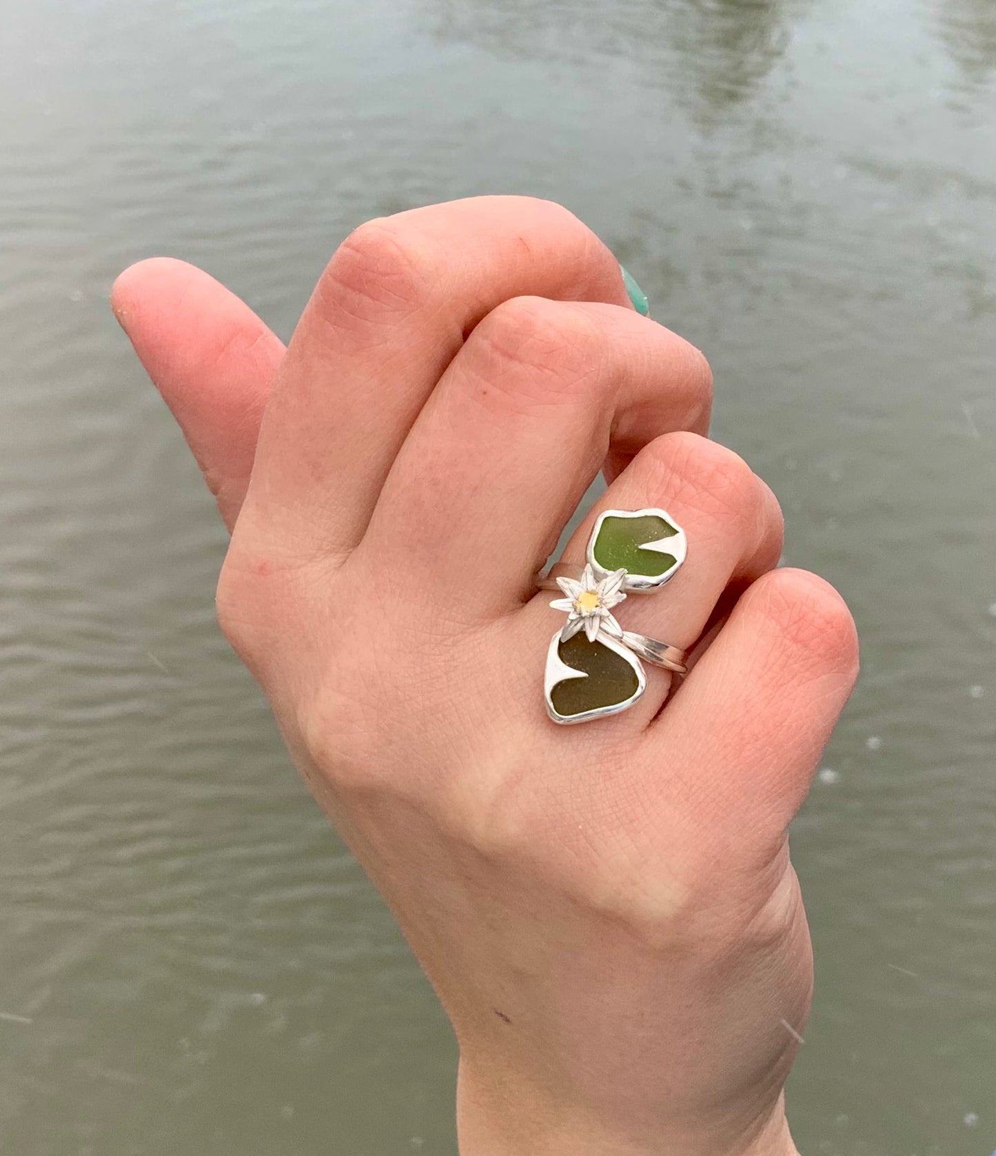 Lumme-sormus kädessä vettä vasten